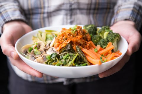 Two hands holding a plate of food