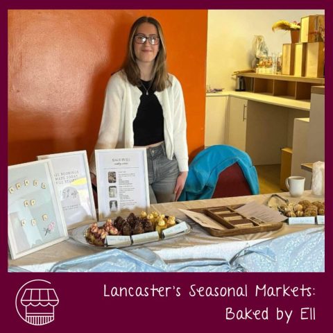 An image of a smiling woman standing behind a table with baked treats on it.